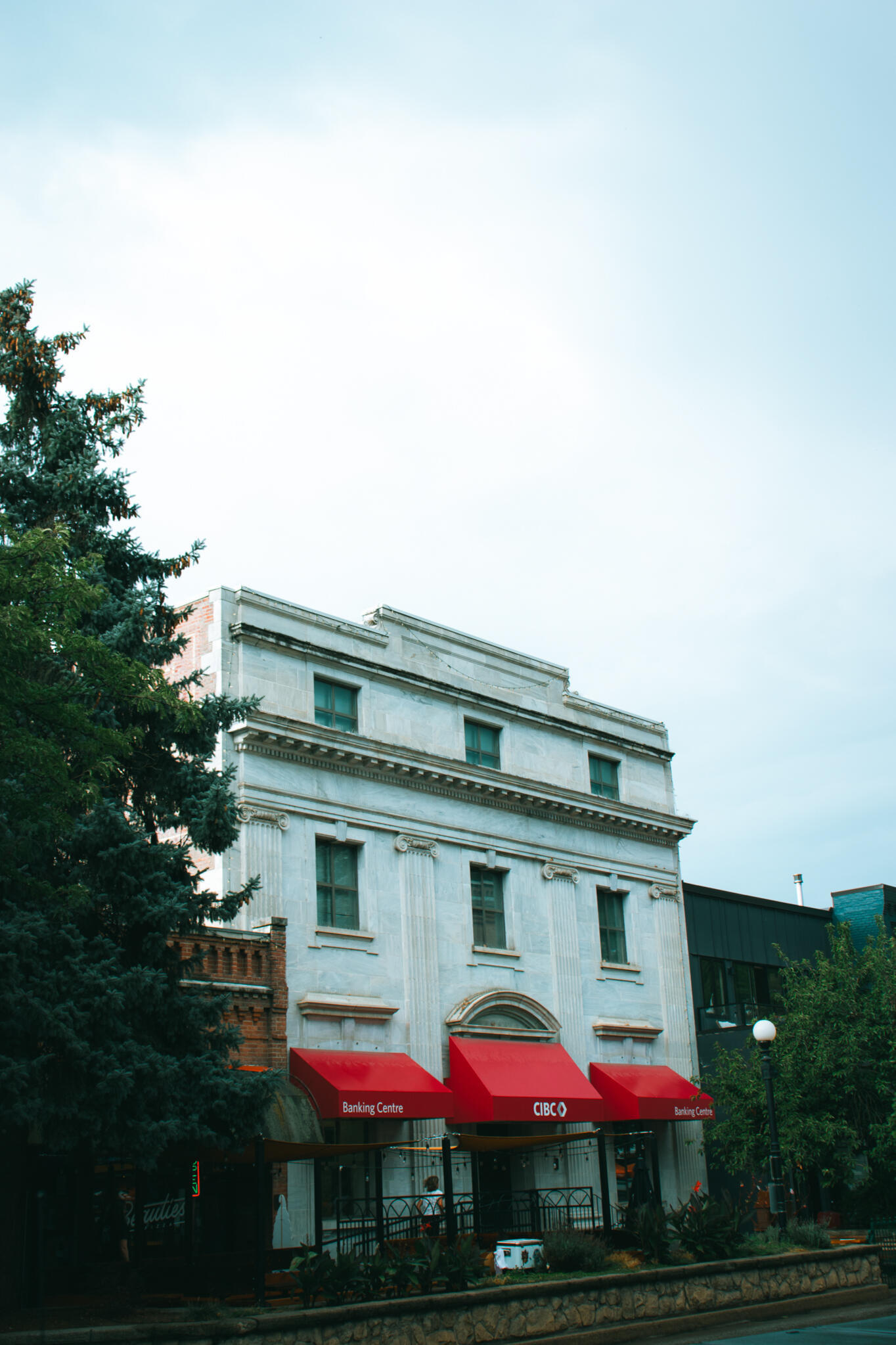 Nelson, British Columbia A large tree stands prominently in front of an old English Victorian style building, providing shade and enhancing the landscape